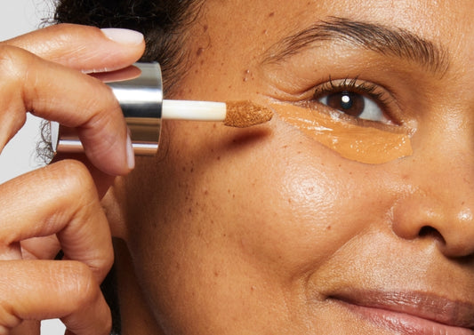Model applies Milk Makeup Future Fluid All Over Cream Concealer to her under eye area.