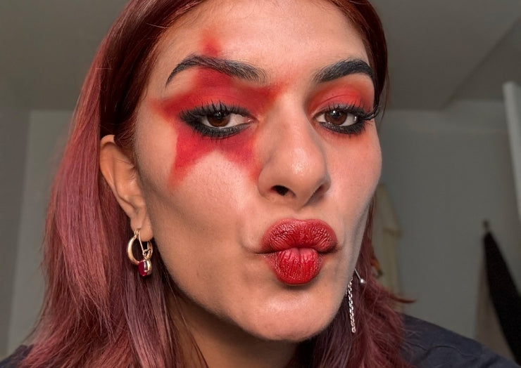 Model wears red star eye makeup and matching red lipstick