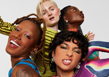 Models pose together wearing full faces of Milk Makeup products against a white background