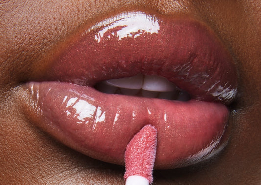 Close-up macro still of a model applying Milk Makeup Odyssey Lip Oil Gloss in Trek.