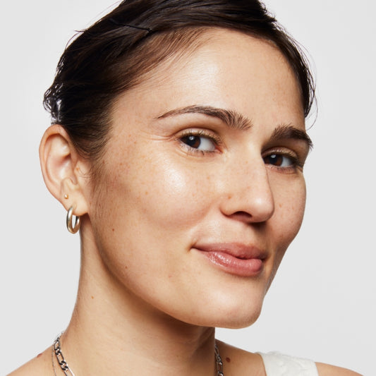 Fresh-faced model poses against a white background after a skincare routine done with Milk Makeup products