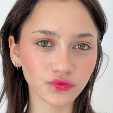 Model wears a jelly lip look done with Milk Makeup Cooling Water Jelly Tint and Odyssey Lip Oil Gloss on a white background