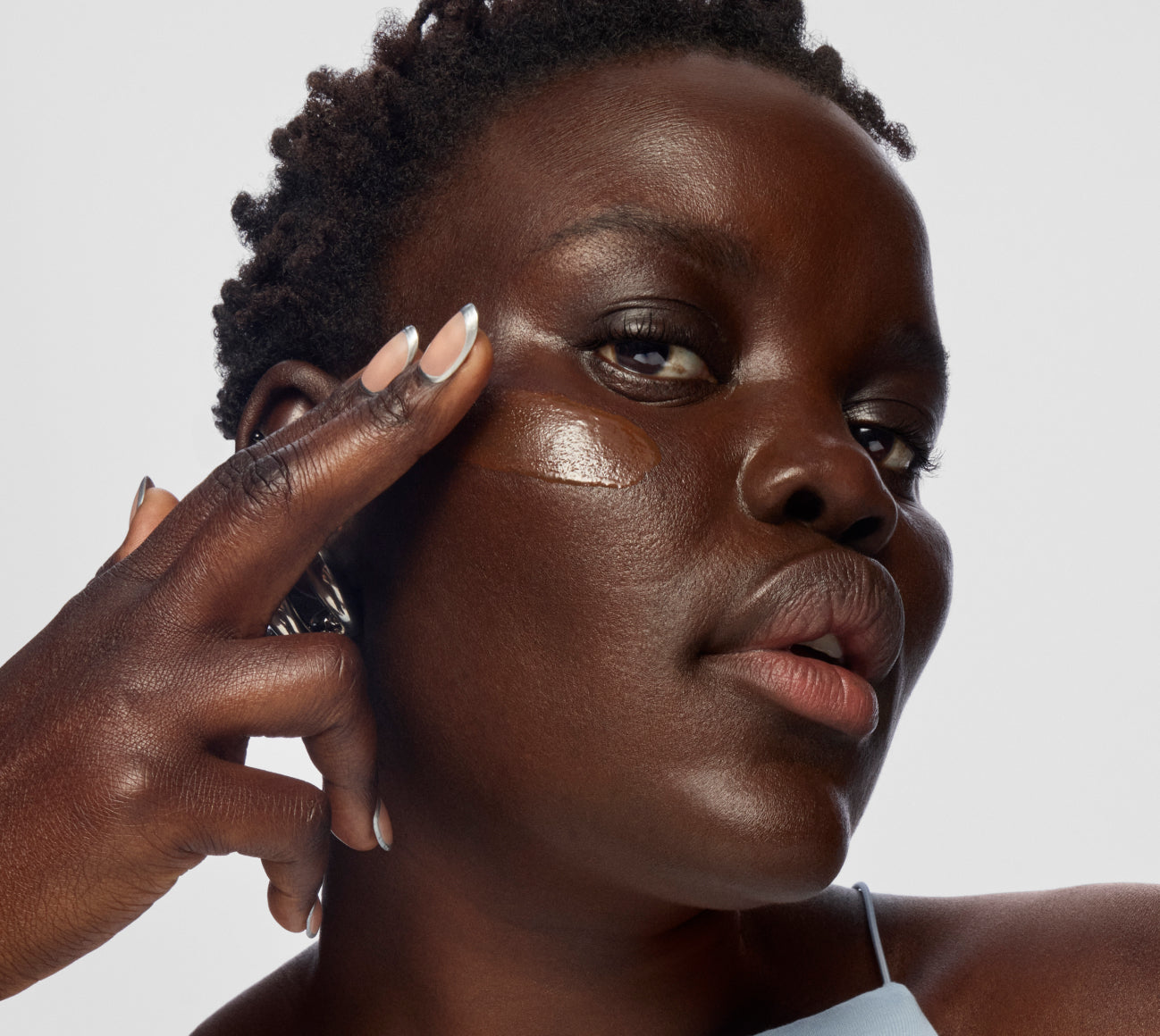 A model applies skin tint foundation