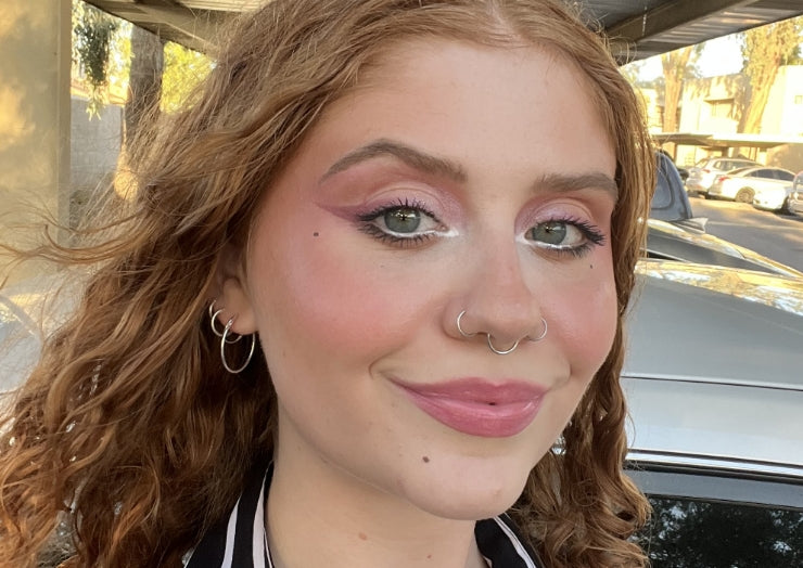 Makeup artist wears a back-to-school makeup look featuring cat-eye liner in a mauve shade.