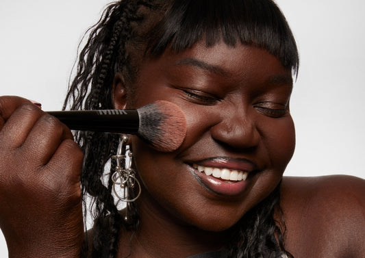Model applies Milk Makeup Pore Eclipse Matte Translucent Setting Powder with Pore Eclipse Setting Powder Brush on a white background