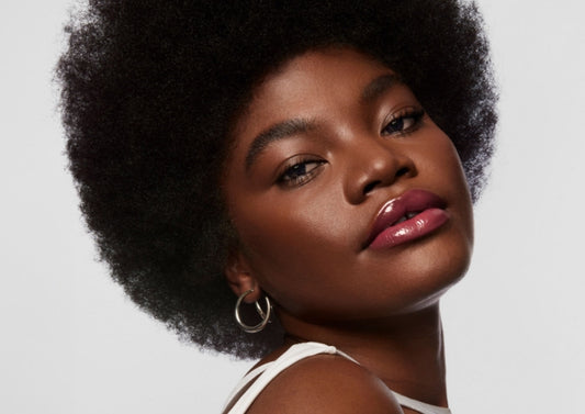 Model wears Milk Makeup Odyssey Lip Oil Gloss in Trek on a white background