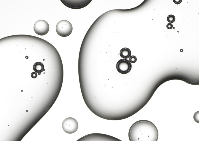 Close up of clear liquid droplets in varying sizes on a white background